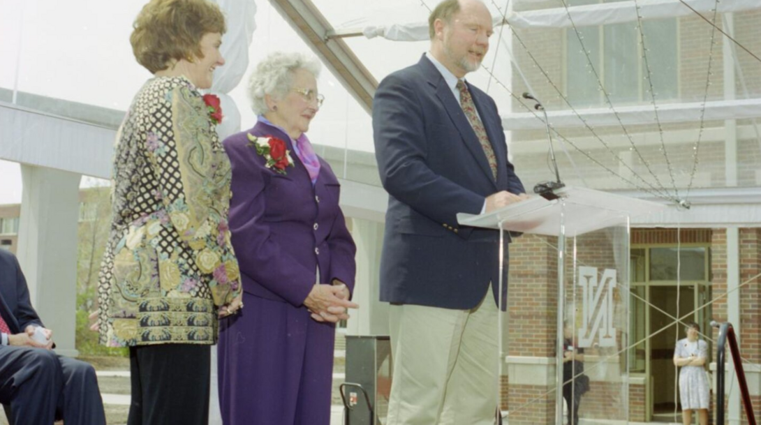 Ed McVaney pictured speaking at the Kauffman Academic Residential Center dedication with Esther Kauffman, Ed's mother-in-law and the building's namesake, at his right.